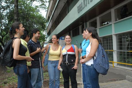 La imagen muestra un grupo de personas frente a la Biblioteca Carlos Monge, algunos de ellos tienen discapacidad visual.