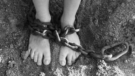 Imagen a blanco y negro de unos pies amarrados con una cadena.