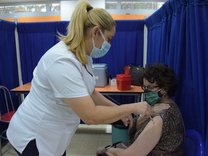 Enfermera vacunando a una adulta mayor.